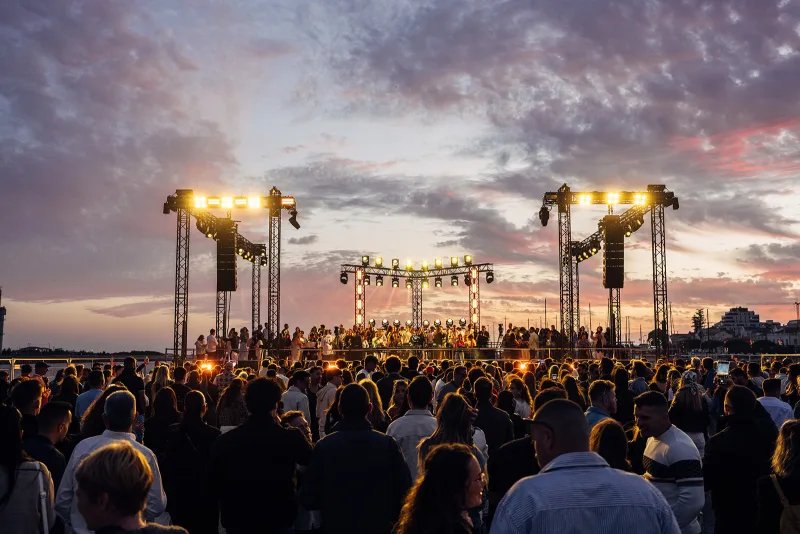 Sunset stage with truss towers, speakers and the dancing crowd